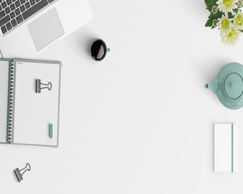 A clean, minimalist office desk with a notebook and coffee